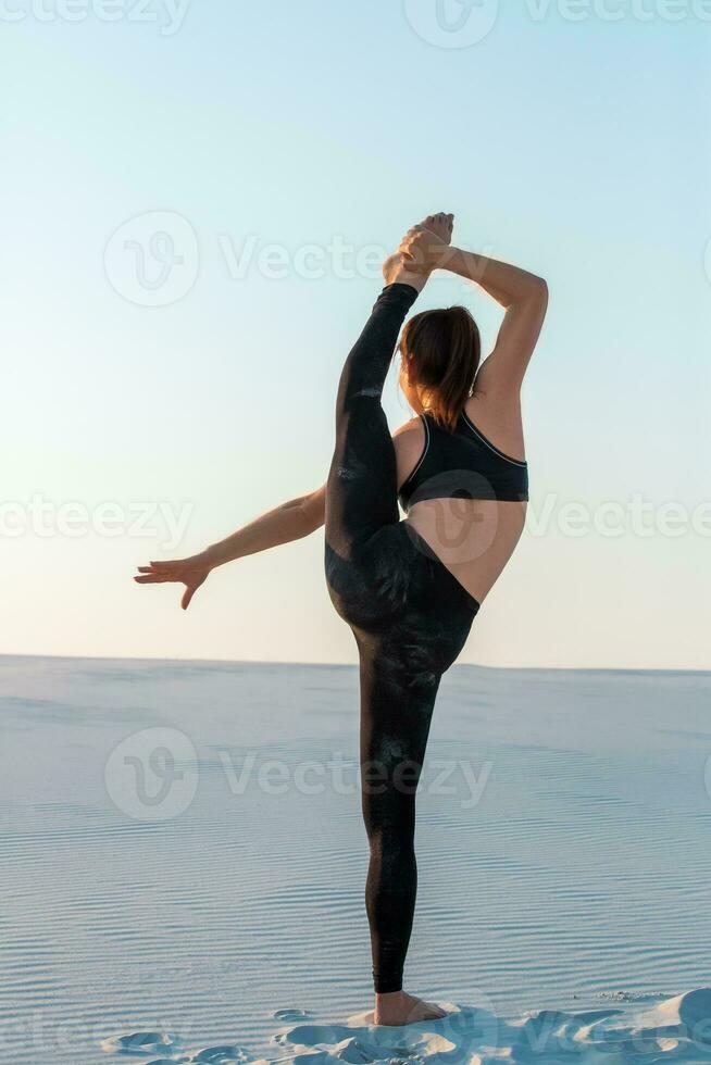 Fitness yoga woman stretching on sand. Fit female athlete doing yoga pose. photo