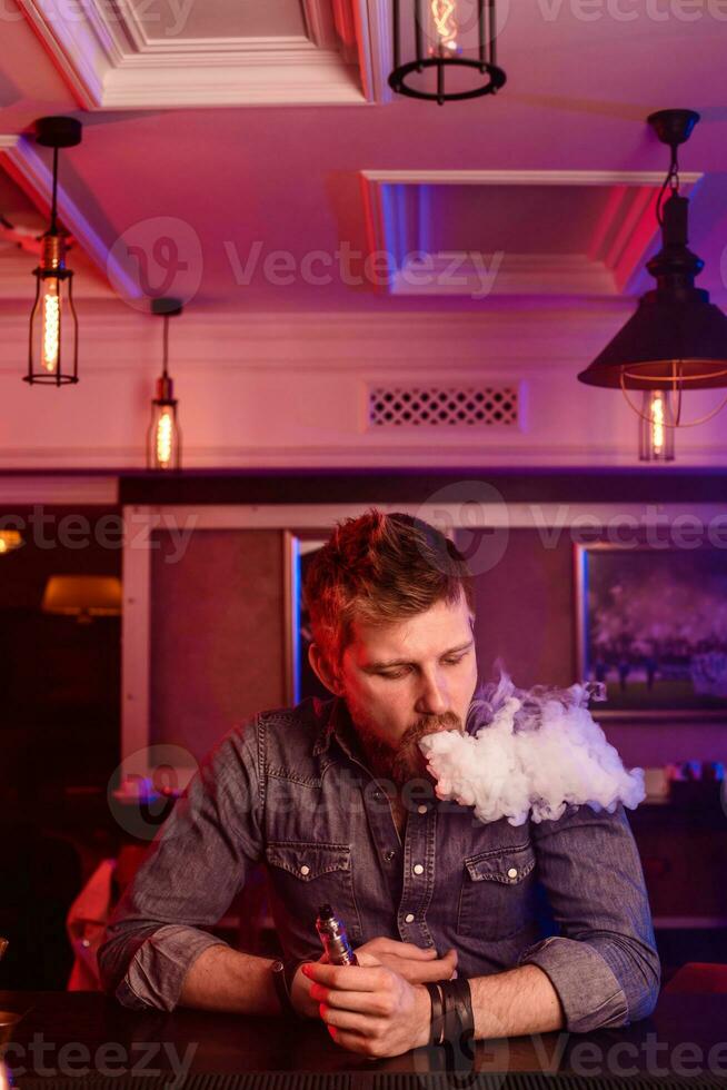 Vape. Vaping man in a cloud of vapor. Photo is taken in a vape bar.