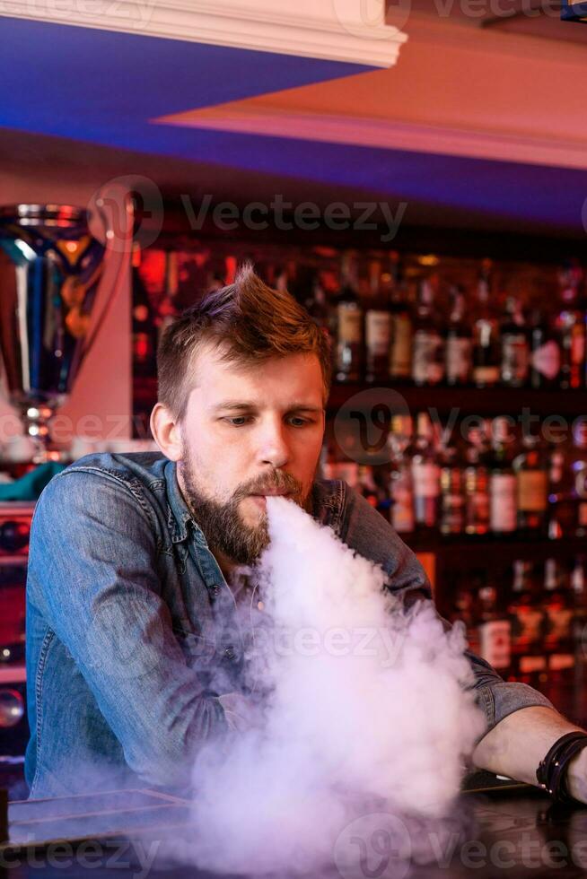 Vape. Vaping man in a cloud of vapor. Photo is taken in a vape bar.
