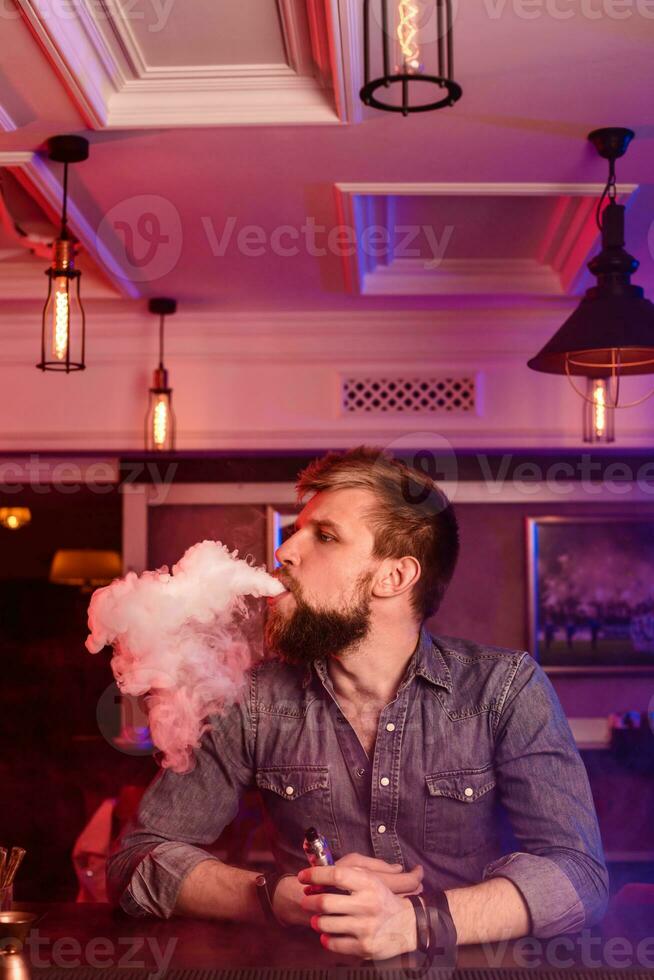 Vape. Vaping man in a cloud of vapor. Photo is taken in a vape bar.