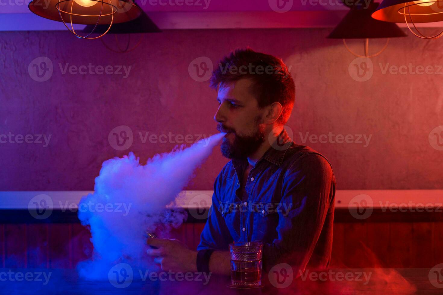 el hombre fumar un electrónico cigarrillo a el vape tienda. foto