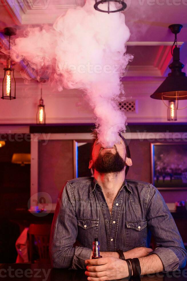 Vape. Vaping man in a cloud of vapor. Photo is taken in a vape bar.
