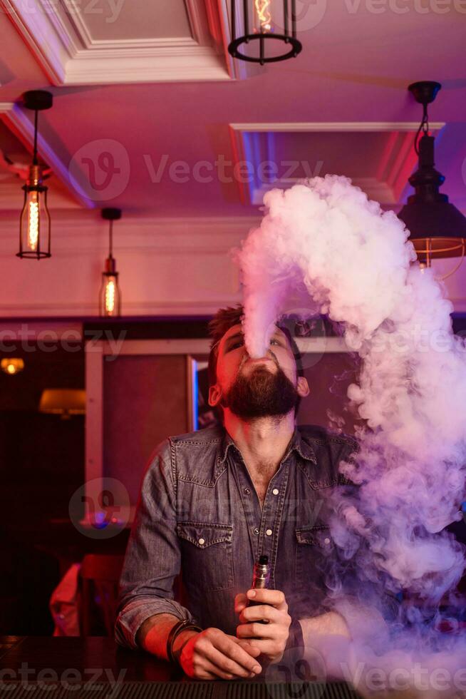 Vape. Vaping man in a cloud of vapor. Photo is taken in a vape bar.