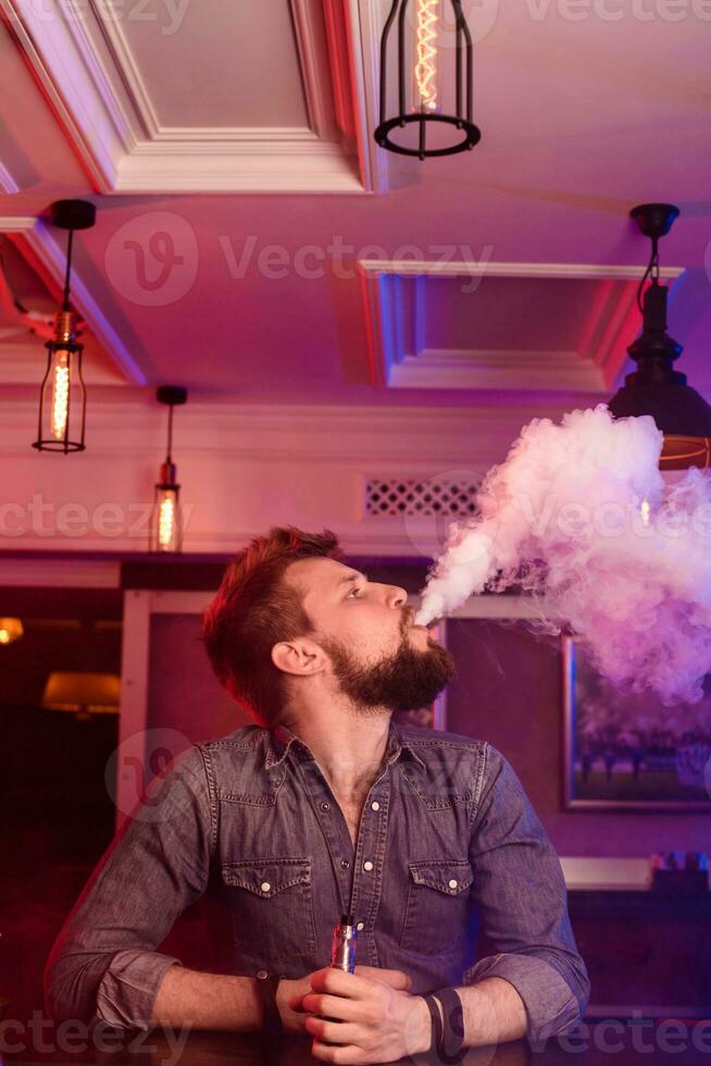 Vape. Vaping man in a cloud of vapor. Photo is taken in a vape bar.