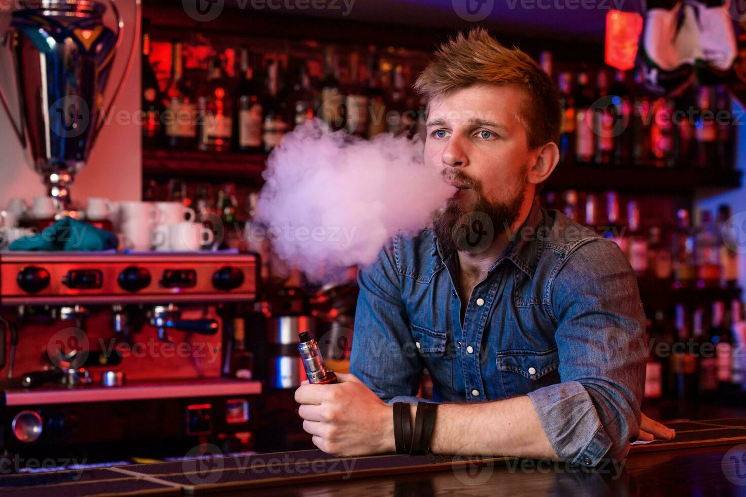 Vape. Vaping man in a cloud of vapor. Photo is taken in a vape bar.