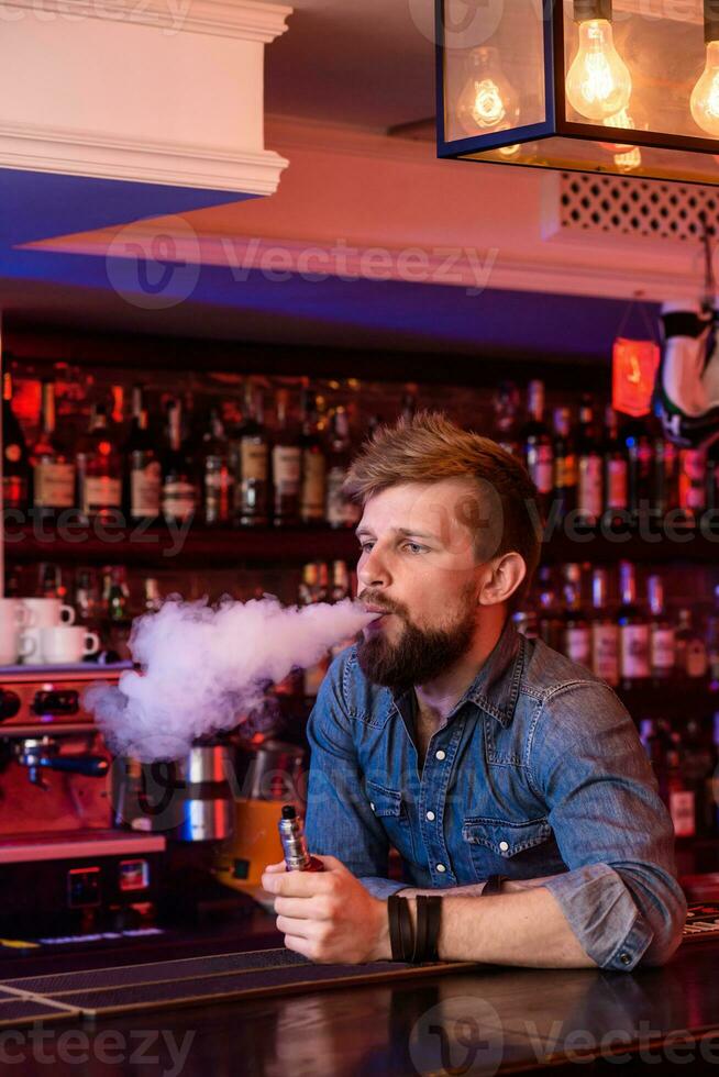 Vape. Vaping man in a cloud of vapor. Photo is taken in a vape bar.