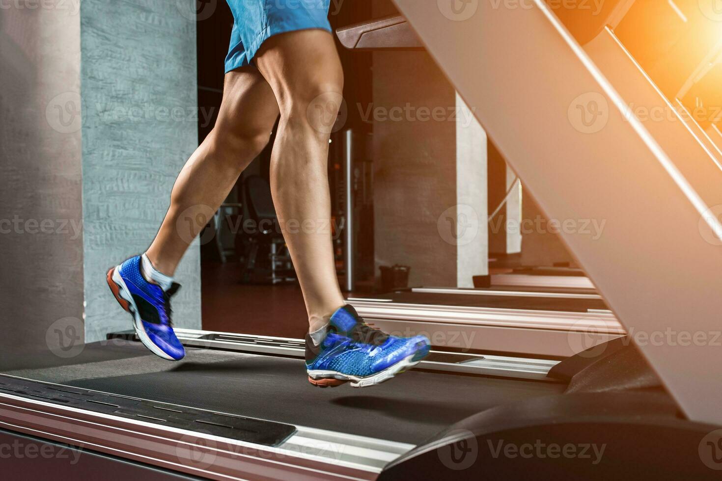 Side view full length of young man in sportswear running on treadmill at gym photo