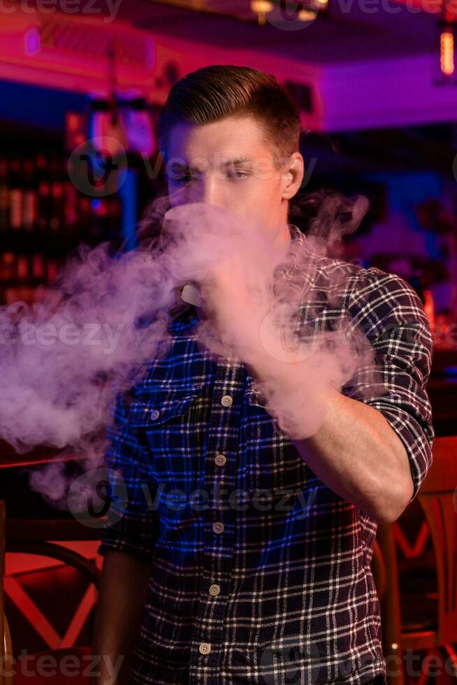 The man smoke an electronic cigarette at the vape shop. photo