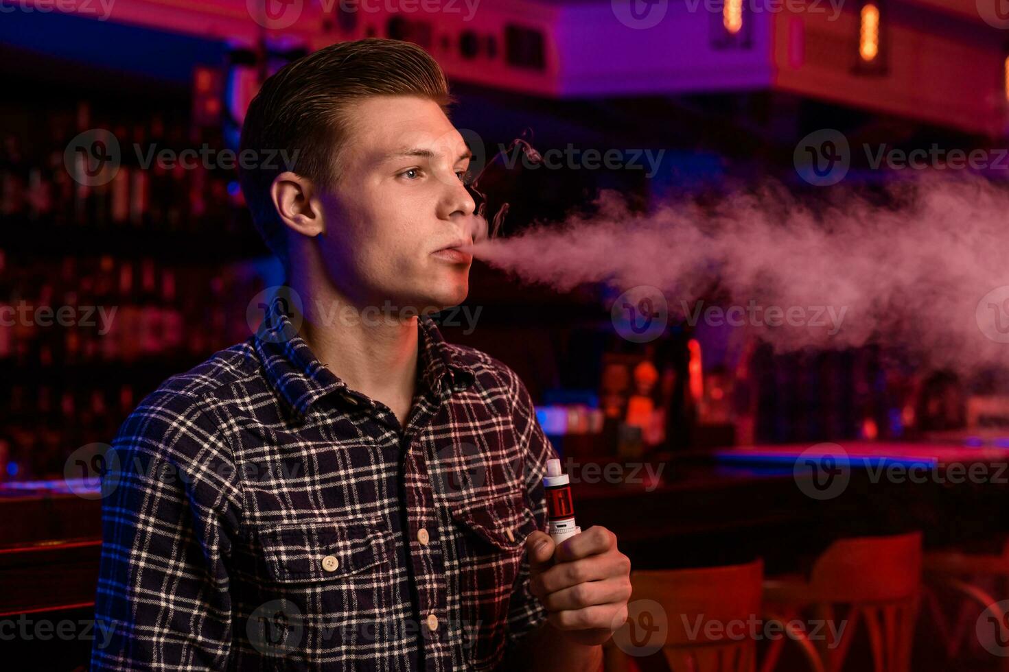 el hombre fumar un electrónico cigarrillo a el vape tienda. foto