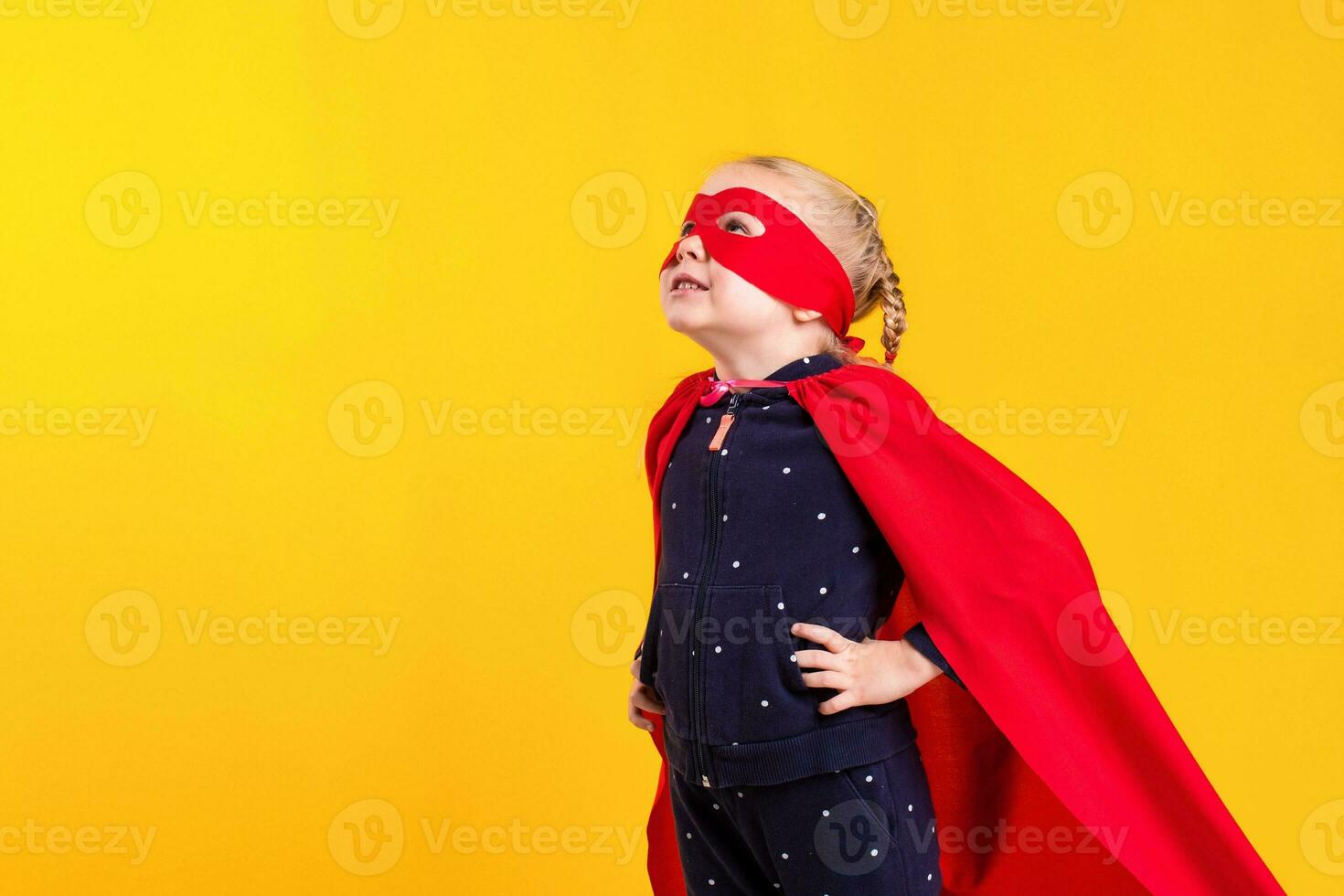 Funny little power superhero child girl in a red raincoat and a mask. Superhero concept. photo