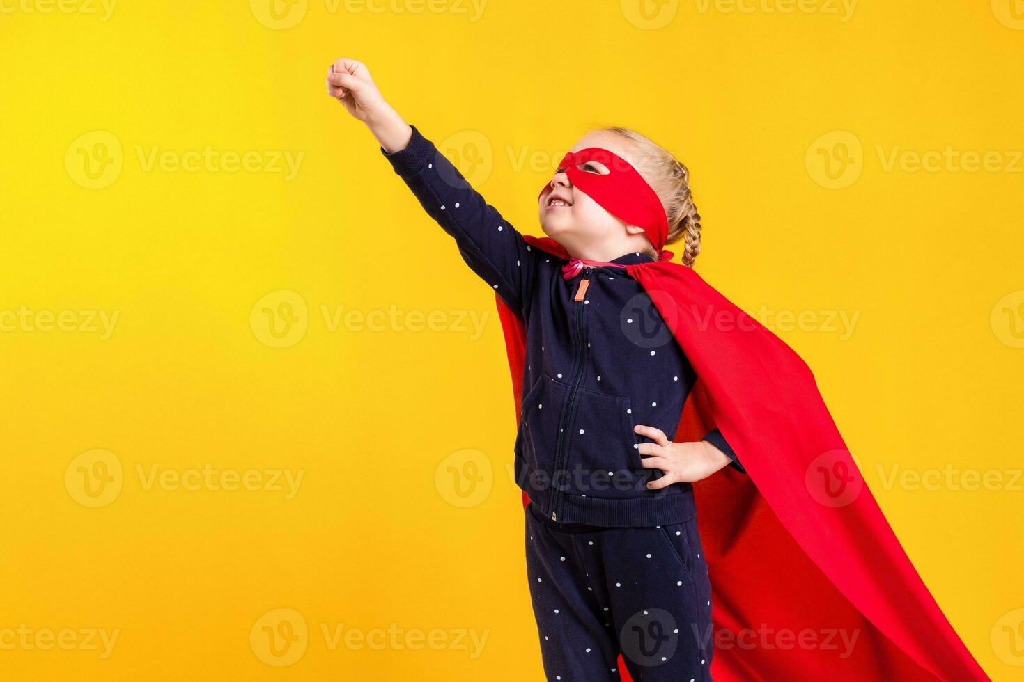 Funny little power superhero child girl in a red raincoat and a mask. Superhero concept. photo