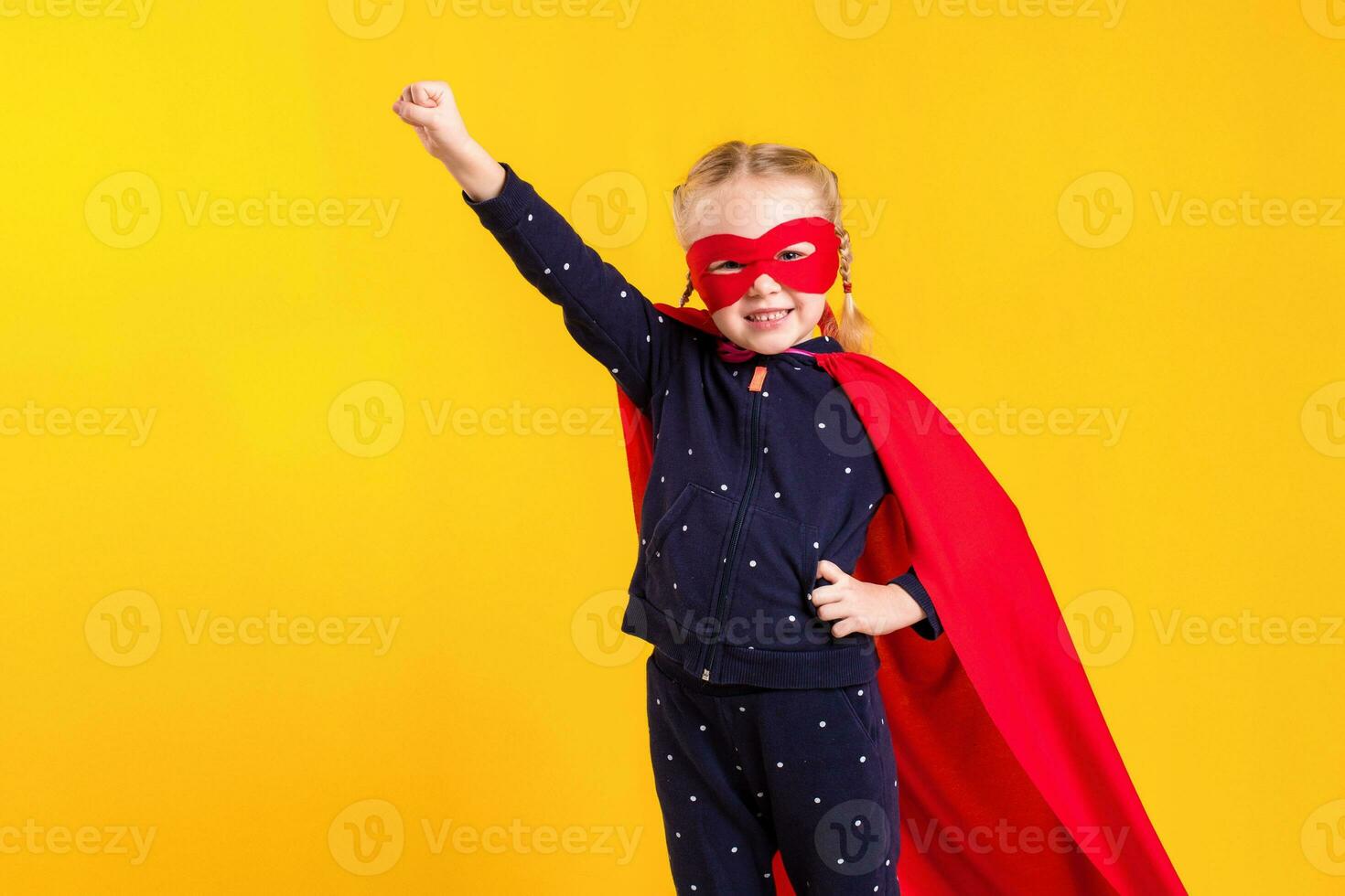 Funny little power superhero child girl in a red raincoat and a mask. Superhero concept. photo