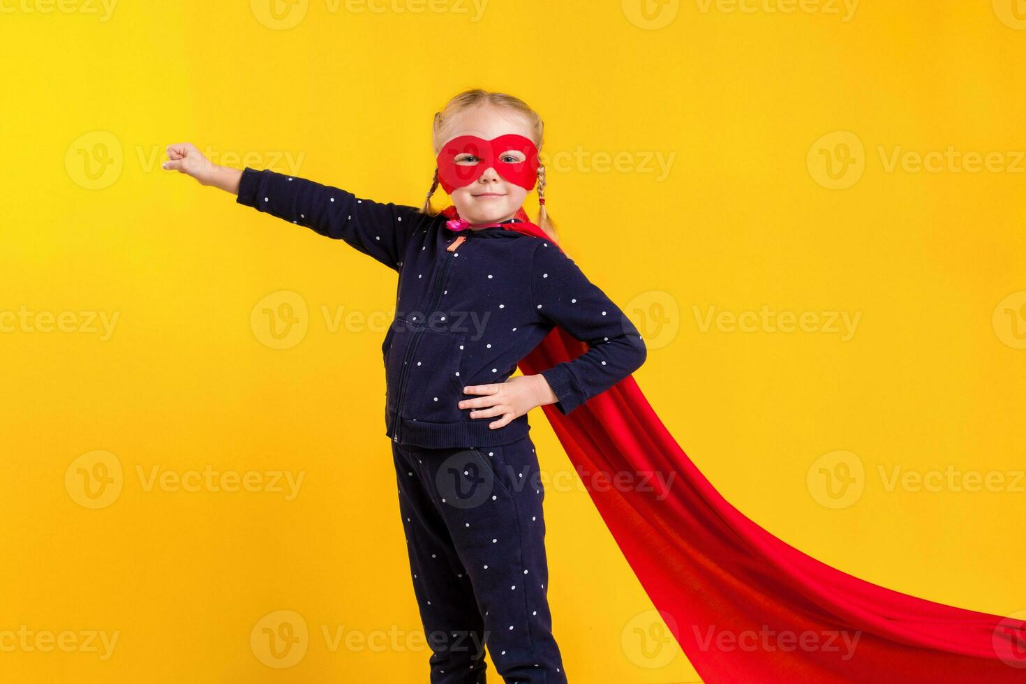 Funny little power superhero child girl in a red raincoat and a mask. Superhero concept. photo