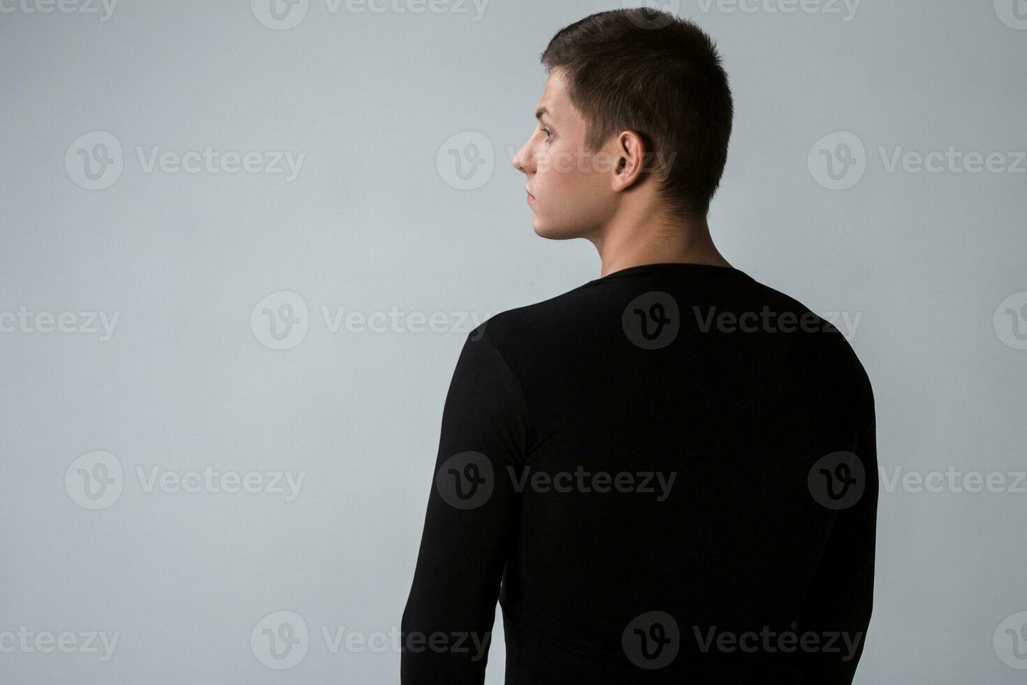 Back view of man in black sweater. Standing young guy. Rear view photo