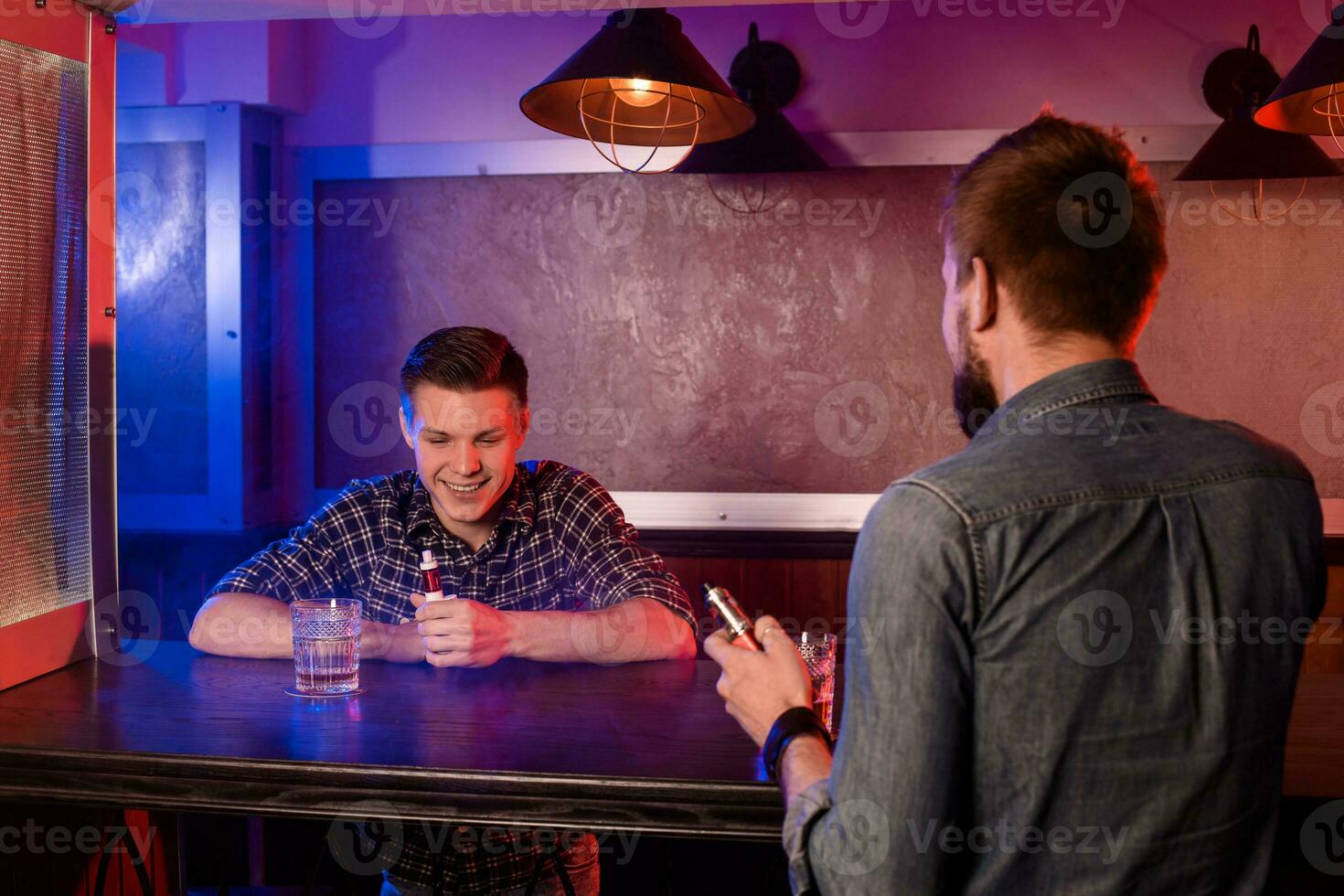 Vaping man holding a mod. A cloud of vapor at the vapebar. photo