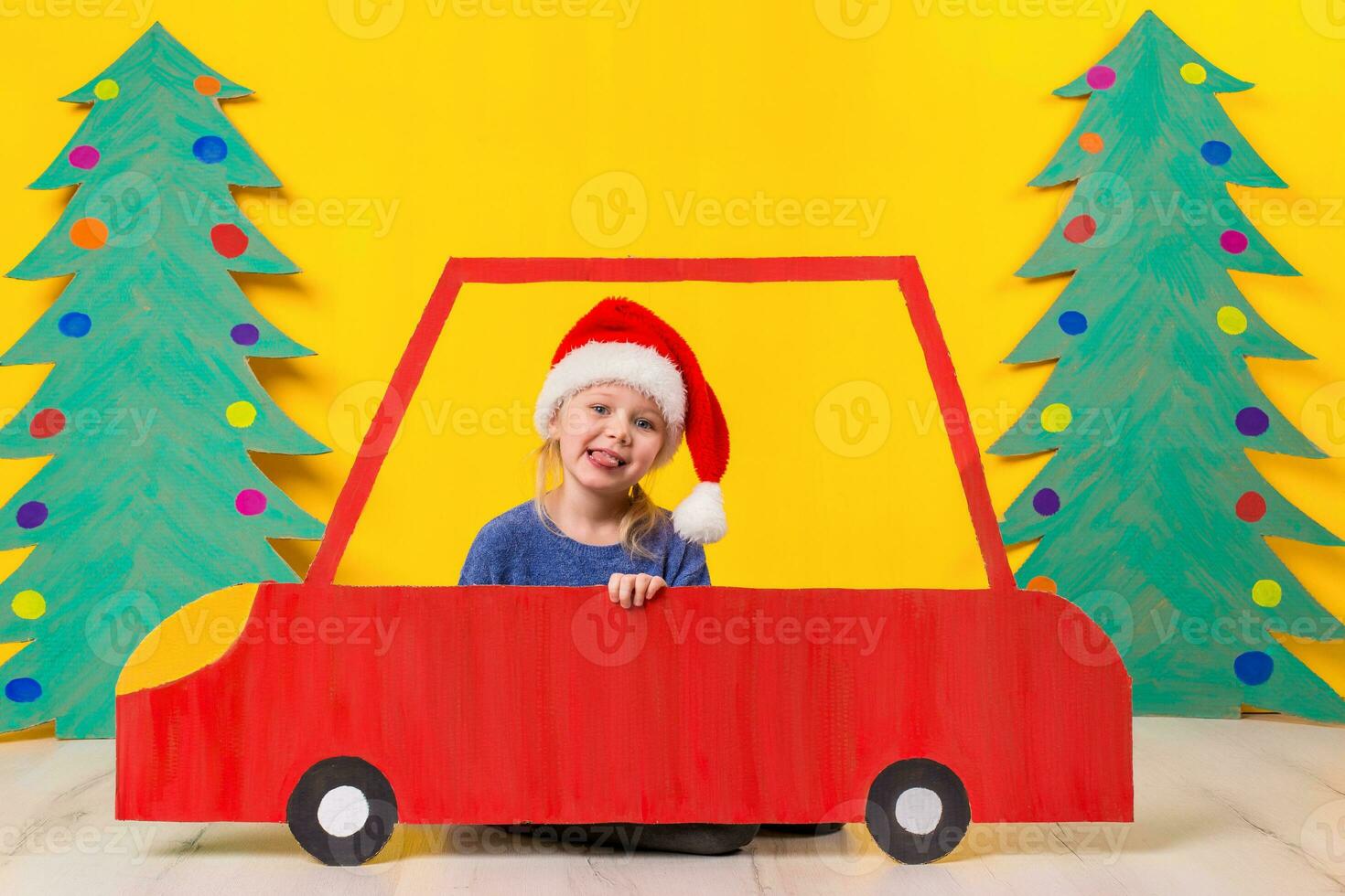 Child with Christmas hat driving a car made of cardboard. Christmas concept. New Year's holidays. photo