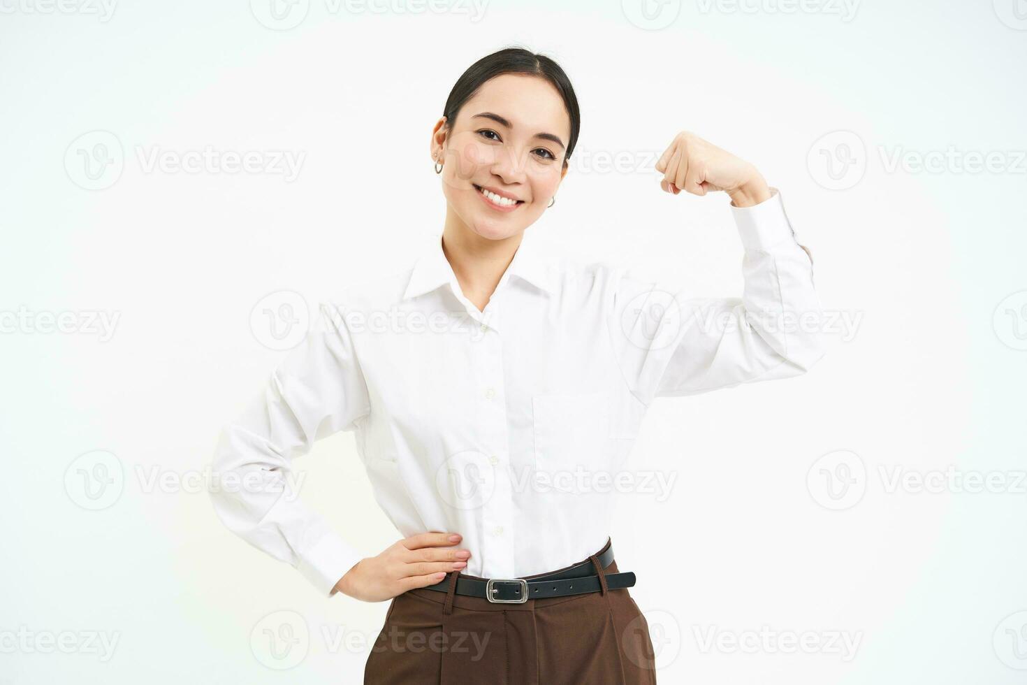 Business and corporate women. Strong and successful asian woman entrepreneur, shows biceps, flexing muscles, smiling pleased, white background photo