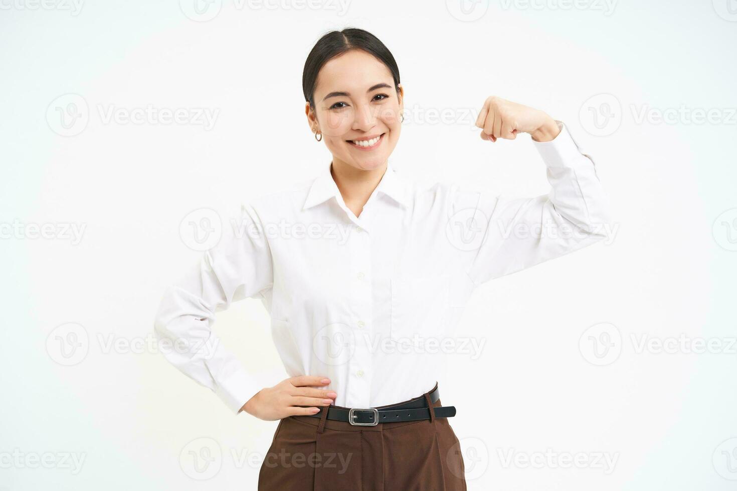 Business and corporate women. Strong and successful asian woman entrepreneur, shows biceps, flexing muscles, smiling pleased, white background photo