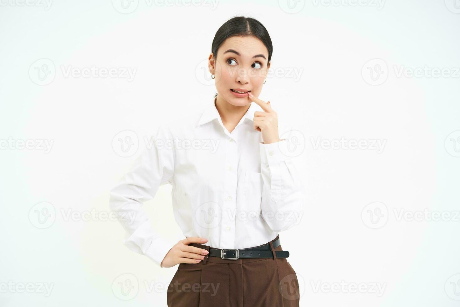 Thoughtful asian woman, businesswoman scratches her face and thinks, makes decision, white background photo