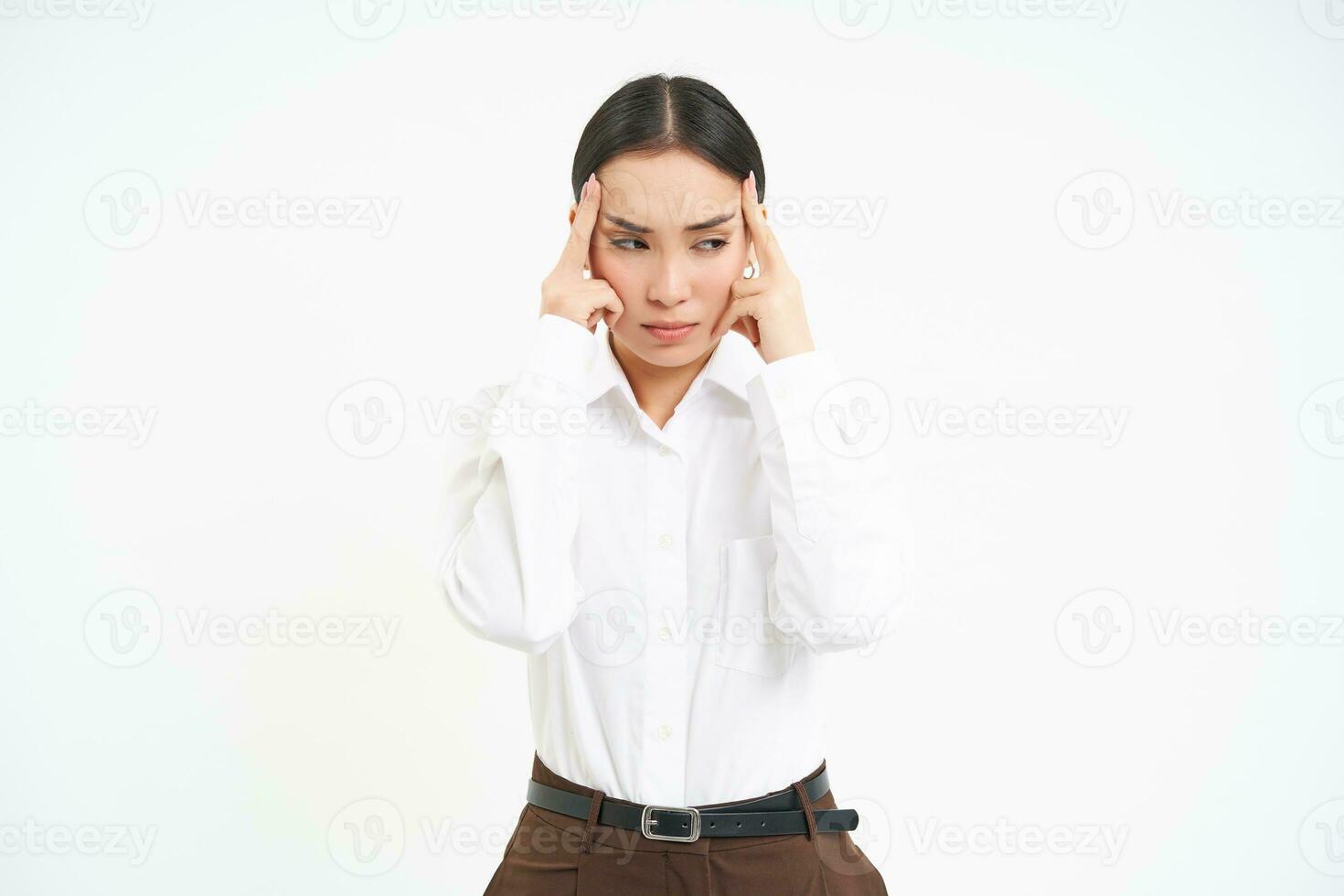 Image of asian serous looking woman, touches her head with upset face expression, has headache, suffers from migraine after stress at work, white background photo