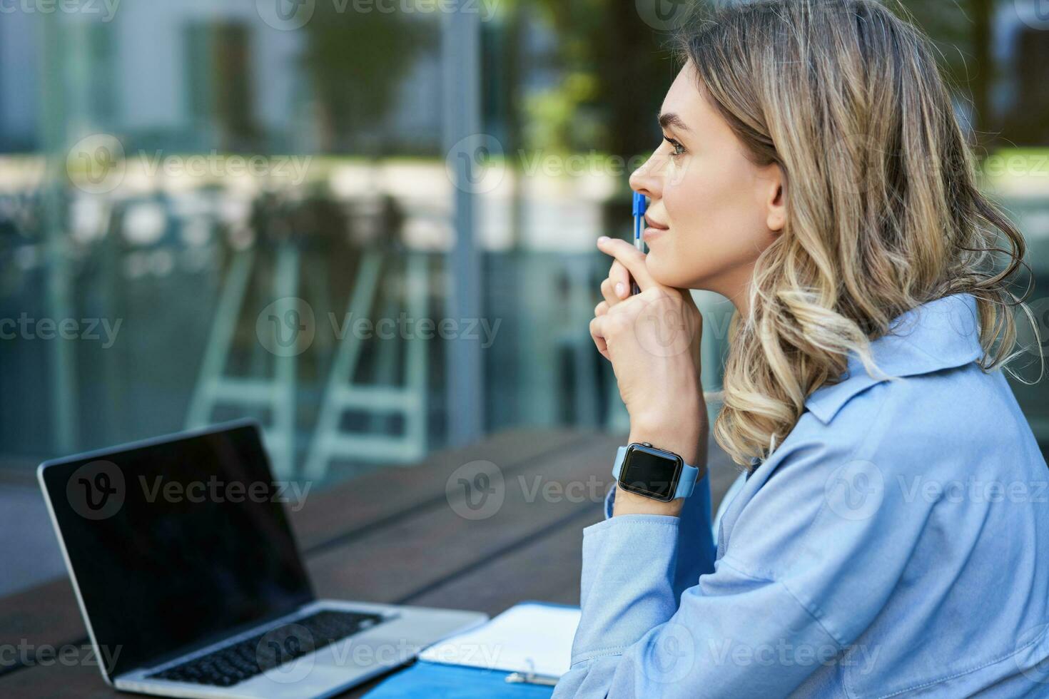 Close up portrait of woman student attend online course classes, sitting outside on fresh air with laptop and taking notes. Businesswoman video chat on computer photo