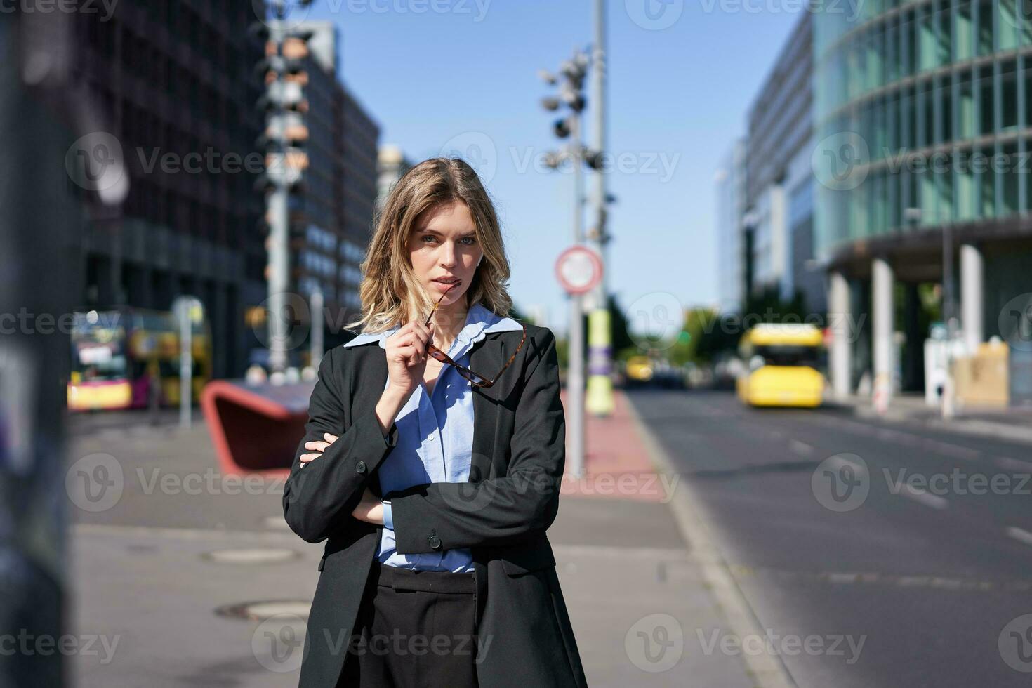 Portrait of confident business woman in suit, cross arms on chest, looking self-assured in city center, standing on street photo