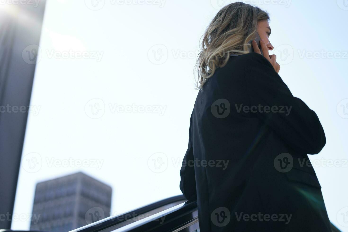 Portrait of stylish corporate woman talking on mobile phone, having a call while walking on street, going to office photo