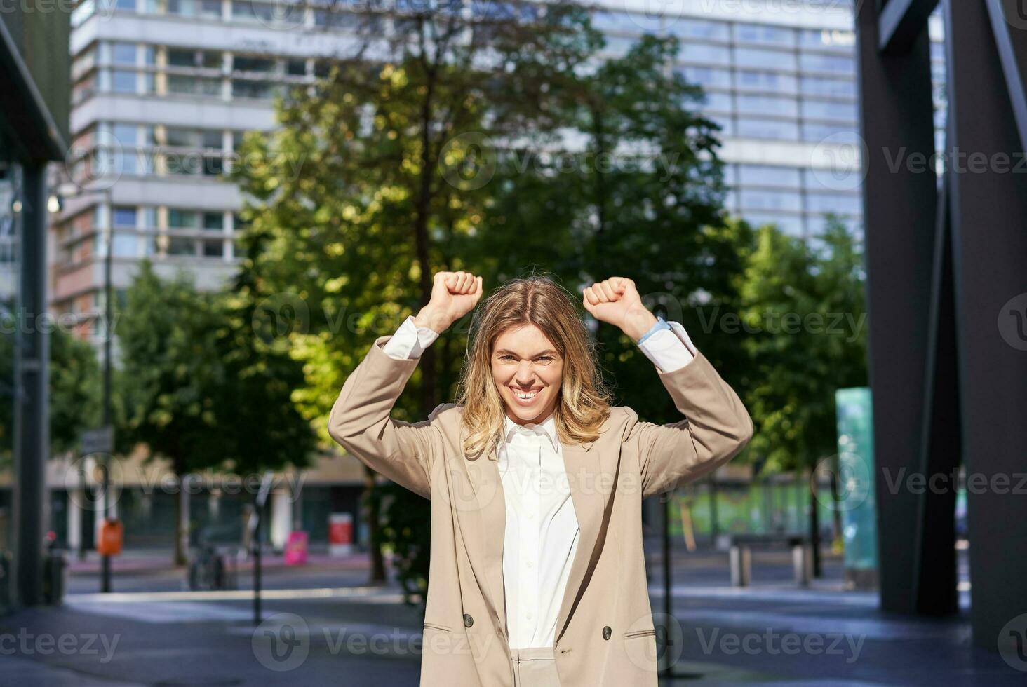 retrato de exitoso negocio mujer, joven corporativo mujer celebrando victoria, logro, triunfando en calle, haciendo puño zapatillas y alegría foto