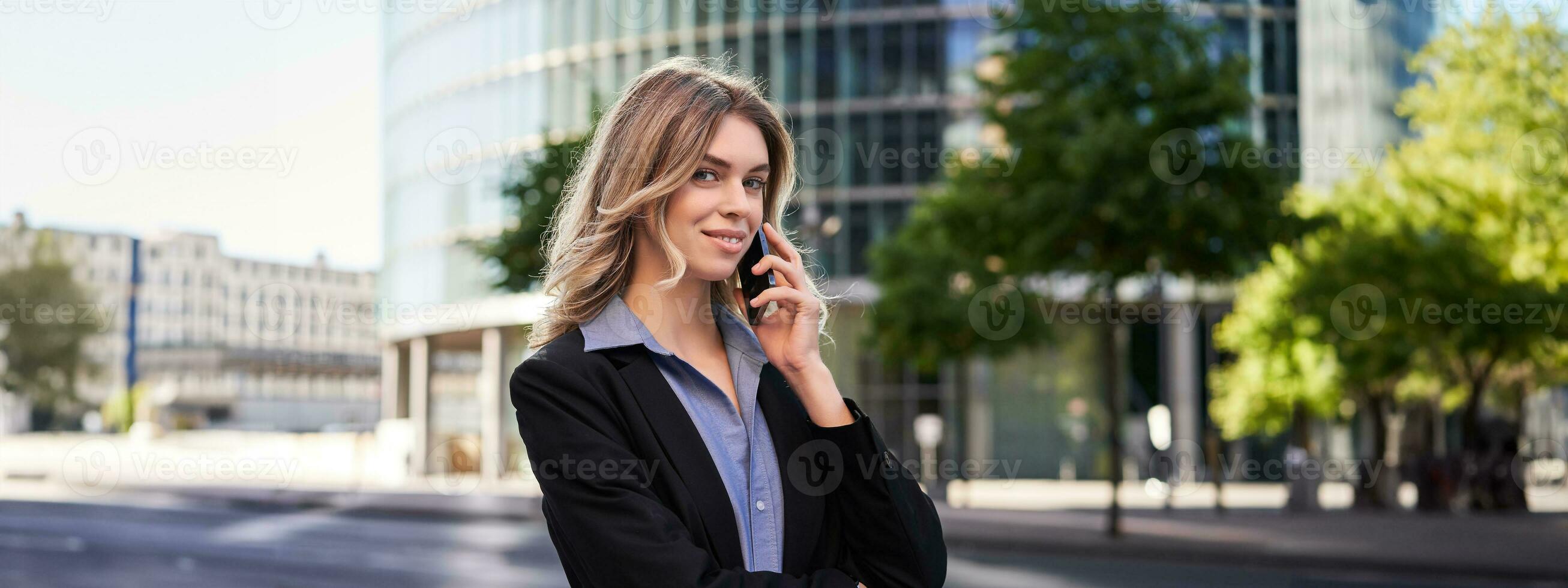 Portrait of successful businesswoman, company ceo walks on street and makes phone calls, talking on smartphone photo