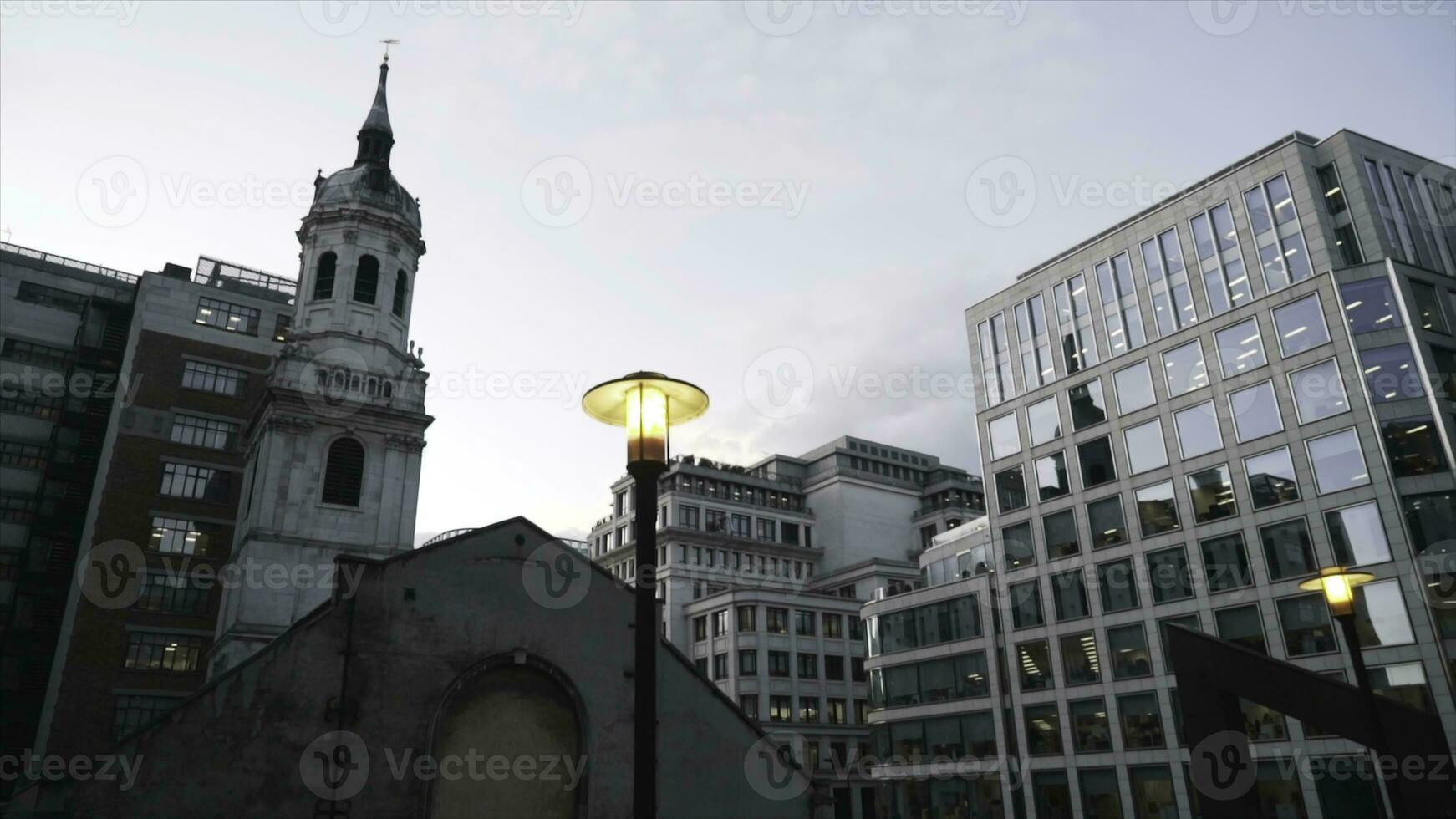 Close-up of yellow street lights in the center of London near the modern glass skyscrapers against the blue evening sky. Action. Evening city scenery photo