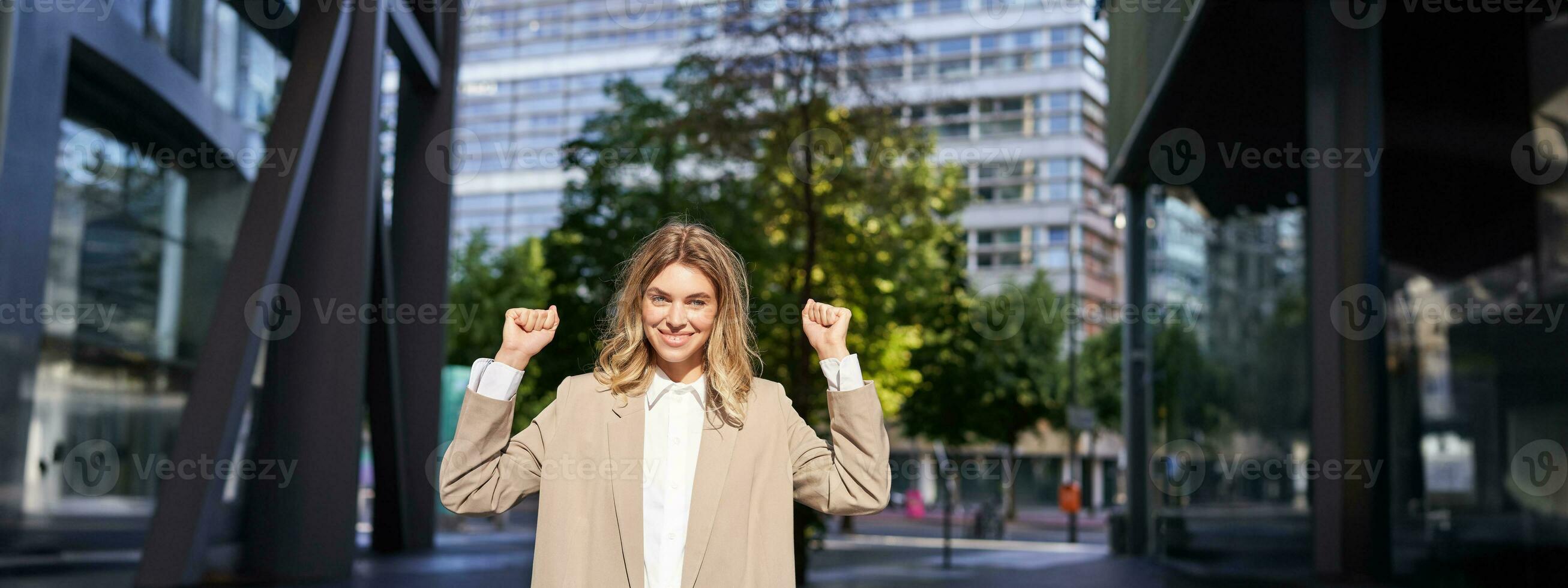 retrato de exitoso negocio mujer, joven corporativo mujer celebrando victoria, logro, triunfando en calle, haciendo puño zapatillas y alegría foto