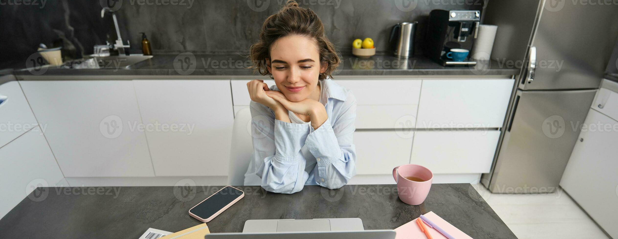 Beautiful brunette woman looking at laptop, sitting at home and studying, doing homework, watching webinar, online course, learning on computer photo