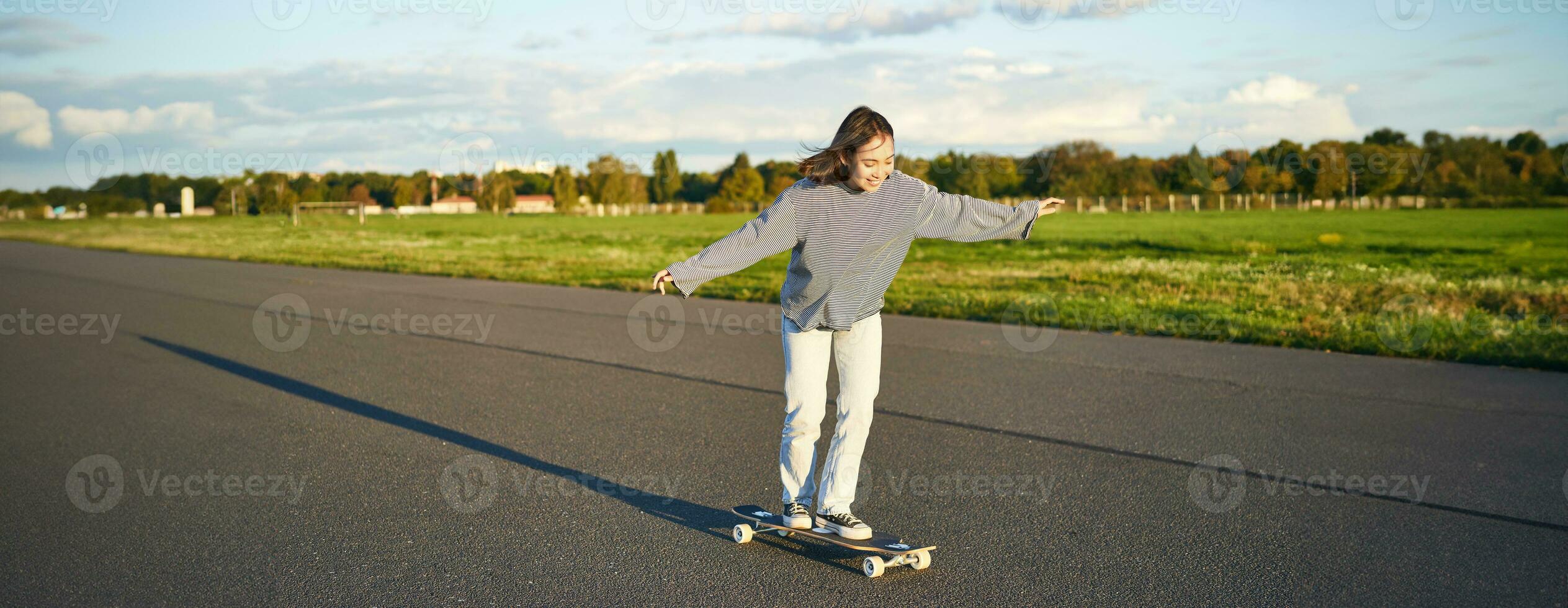 Hobbies and lifestyle. Young woman riding skateboard. Skater girl enjoying cruise on longboard on sunny day outdoors photo