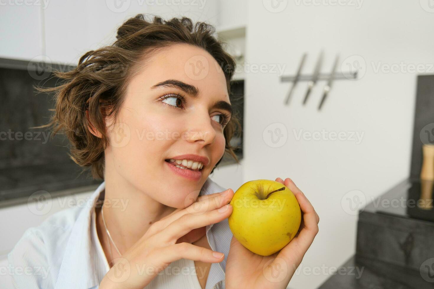 Close up portrait of healthy, beautiful young woman holding an apple, smiling photo