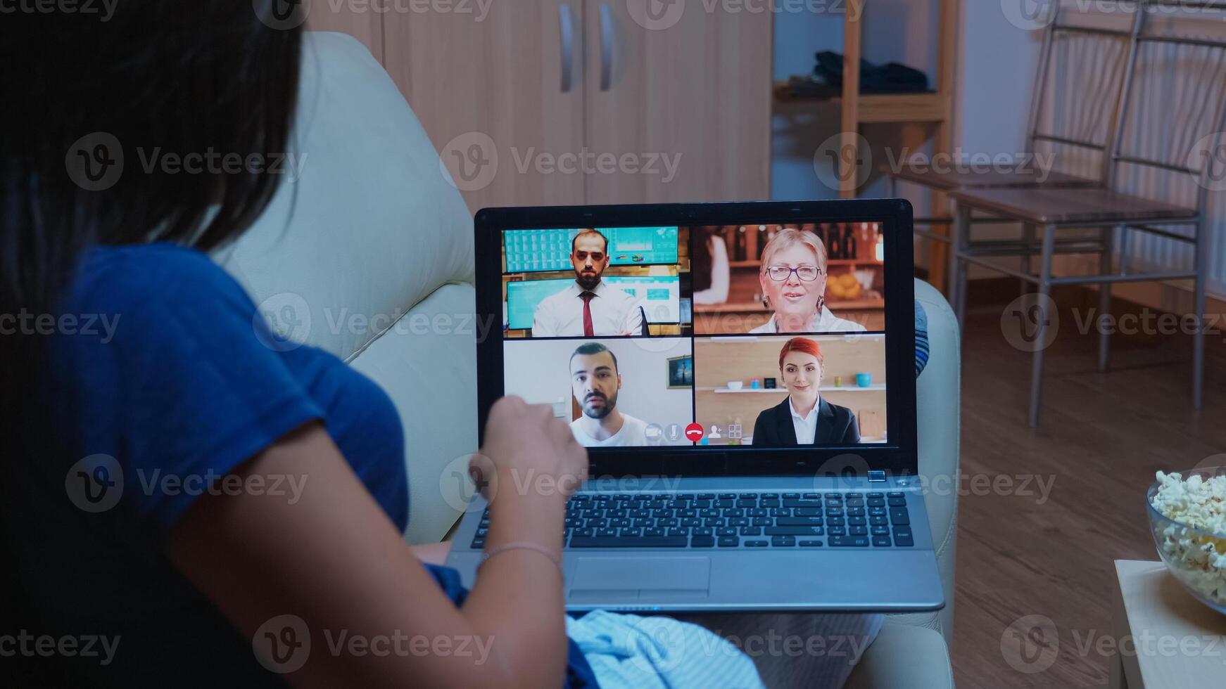 Woman talking with business people on webcam. Remote worker having online meeting, video conference consulting with colleagues on videocall working in front of laptop at home lying on couch photo