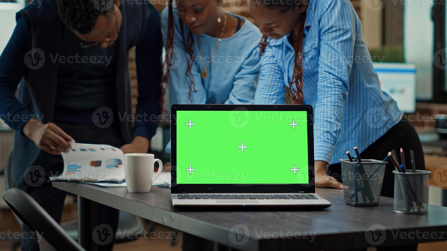 People using laptop with green screen on table, having isolated copyspace display in meeting to review annual data reports. Startup team checking papers, working with blank mockup. Tripod shot. photo