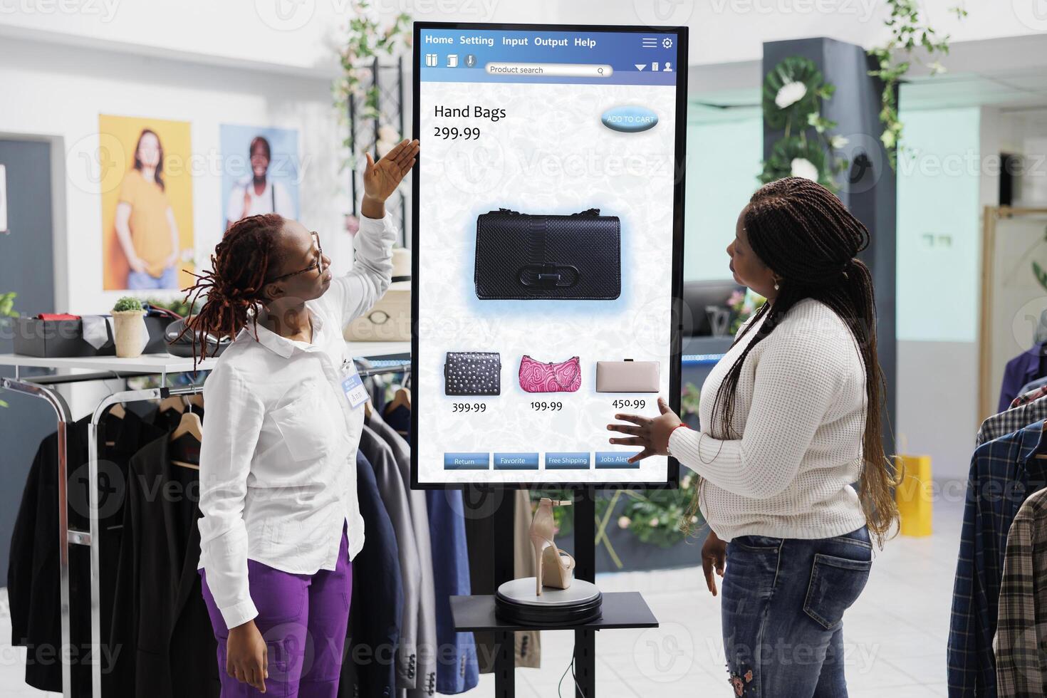 Woman employee showing clothes to client in front of self service checkout kiosk, advising to purchase fashion items in clothing store. Young client talking to assistant about merchandise on board. photo
