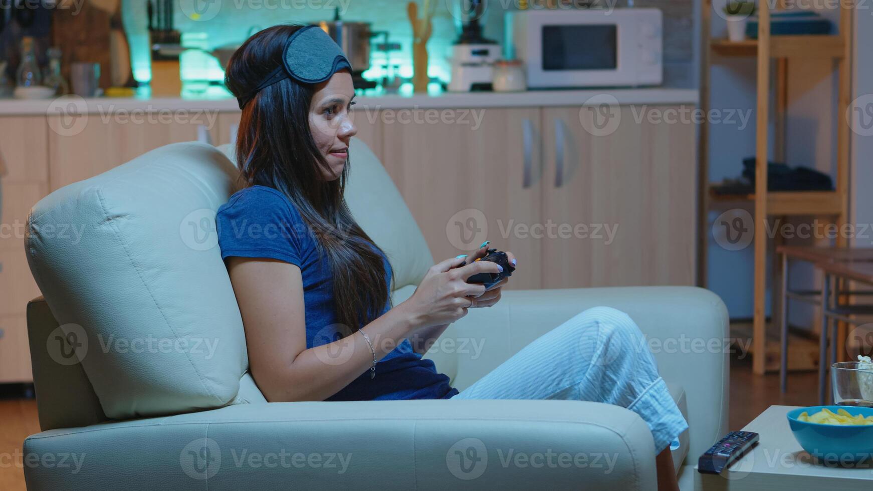 Gamer woman playing video games on console using controller and joysticks sitting on couch in front of TV. Excited determined person relaxing gaming with wireless controller having fun winning photo