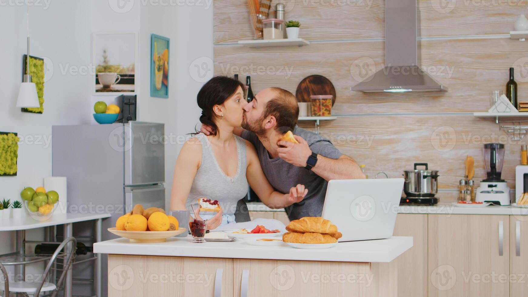 Entrepreneur late at work during breakfast with wife in kitchen. Stressed out man late hurrying nervous running fast to meeting, hurry to work, late for appointment. Kissing wife goodbuy and running to office photo