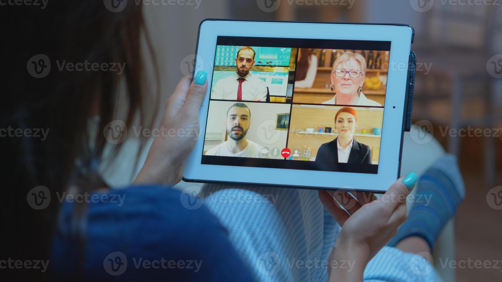 Woman listening online training on tablet late at night sitting on sofa. Remote worker having virtual meeting consulting with colleagues on videocall and webcam chat using internet technology. photo
