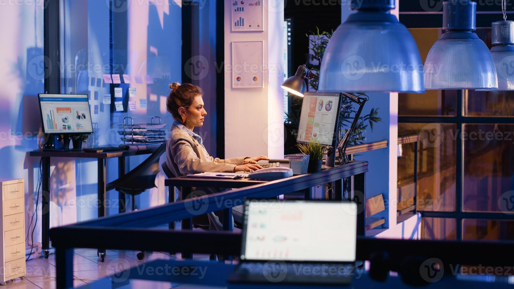 Woman employee looking at startup analytics on pc, working after hours to help increase business profit. Startup advisor analyzing investment strategy for development, research plan. photo