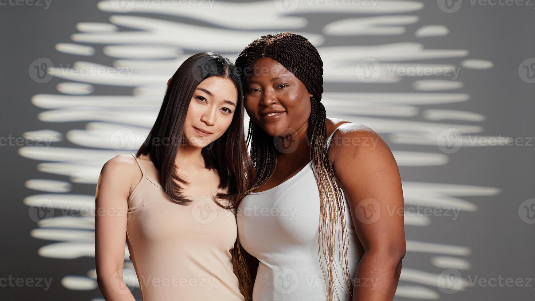Group of friends expressing femininity in studio, filming beauty ad campaign and acting glamorous. Diverse skinny and curvy women with different skintones posing on camera, self love. photo