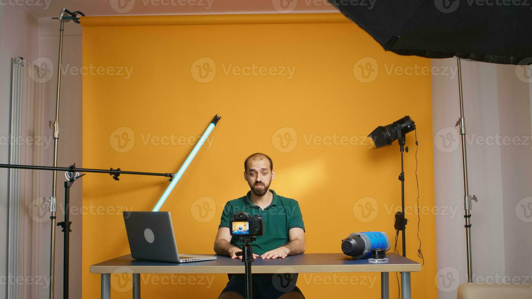 famoso vlogger grabación vídeo para suscriptores mirando a el cámara en estudio. social medios de comunicación podcast y revisar, blogging vlogueo, digital Internet web era, hombre de influencia grabación para en línea distribución foto