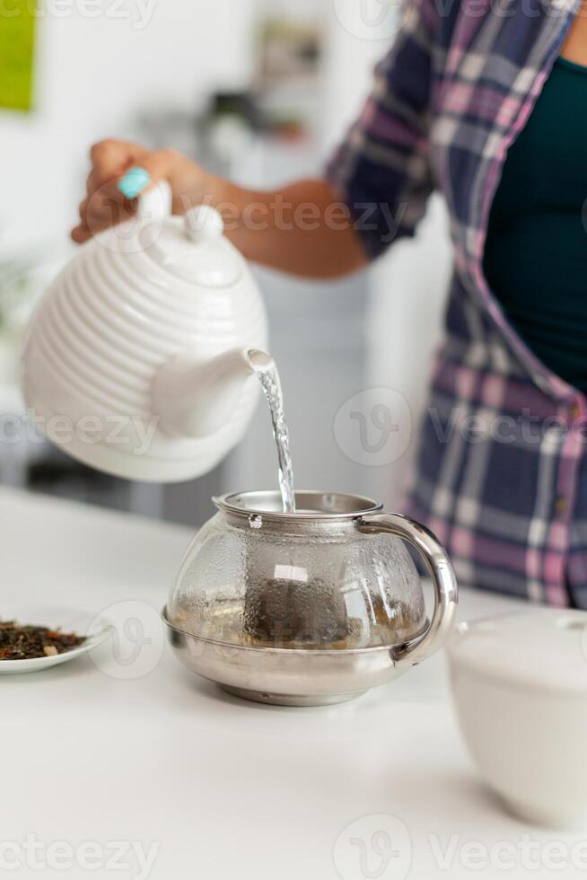 Close up of pouring hot water over natural aromatic herbs to make tea. Woman, lifestylem, beverage, preparation, herbal, teapot, morning, aromatic, lifestyle photo
