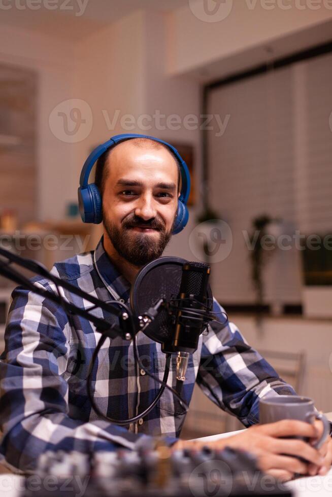 New media star smiling announcing contest winner during his live podcast in home studio using professional gear. Creative online show On-air production internet broadcast host streaming live content photo