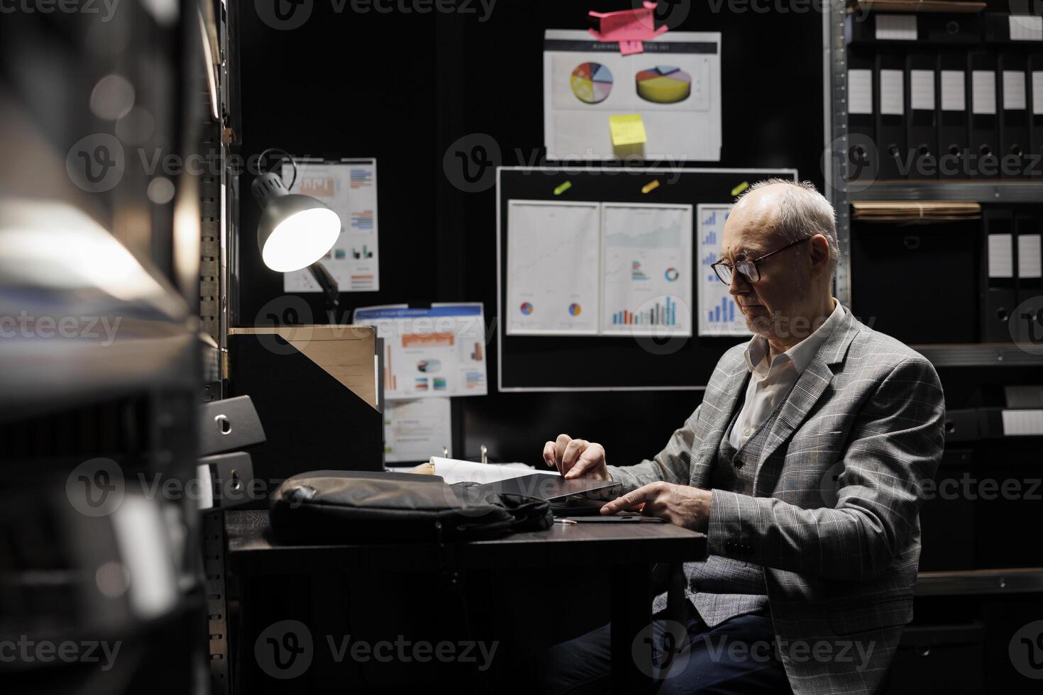 Senior businessman packing laptop up in office suitcase bag preparing to clock out and leave work. Bookkeeping executive in business accountancy company file cabinet repository photo