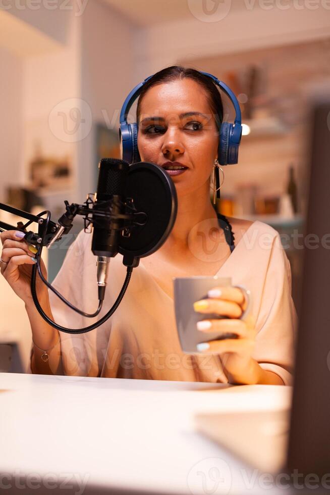 Talking on professional microphone during vlog recording in kitchen. On-air online production internet broadcast show host streaming live content, recording digital social media communication photo