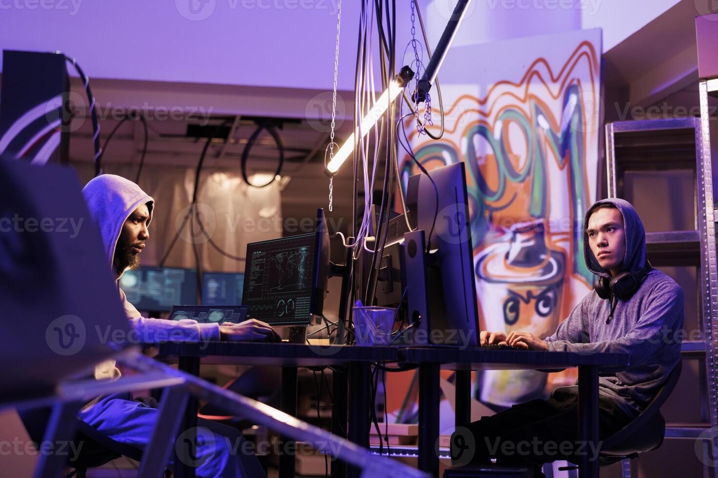 Hackers breaking law while coding dangerous computer virus in abandoned warehouse. Criminals working together and programming illegal malicious software in hideout workspace photo