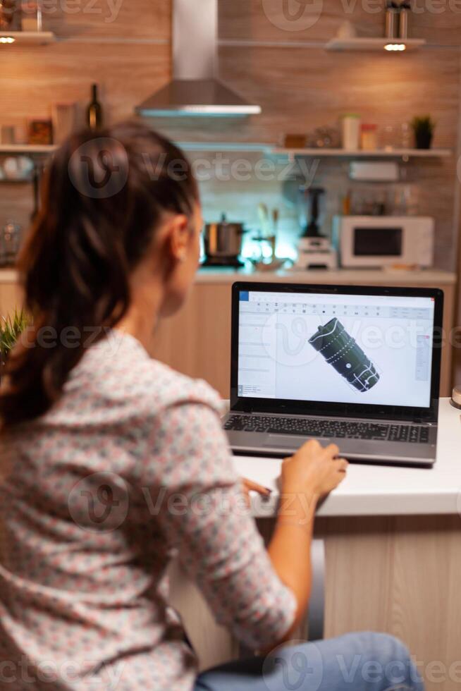 Back view of engineer working on turbine project in home office during night time. Industrial female engineer working on personal computer showing cad software. photo