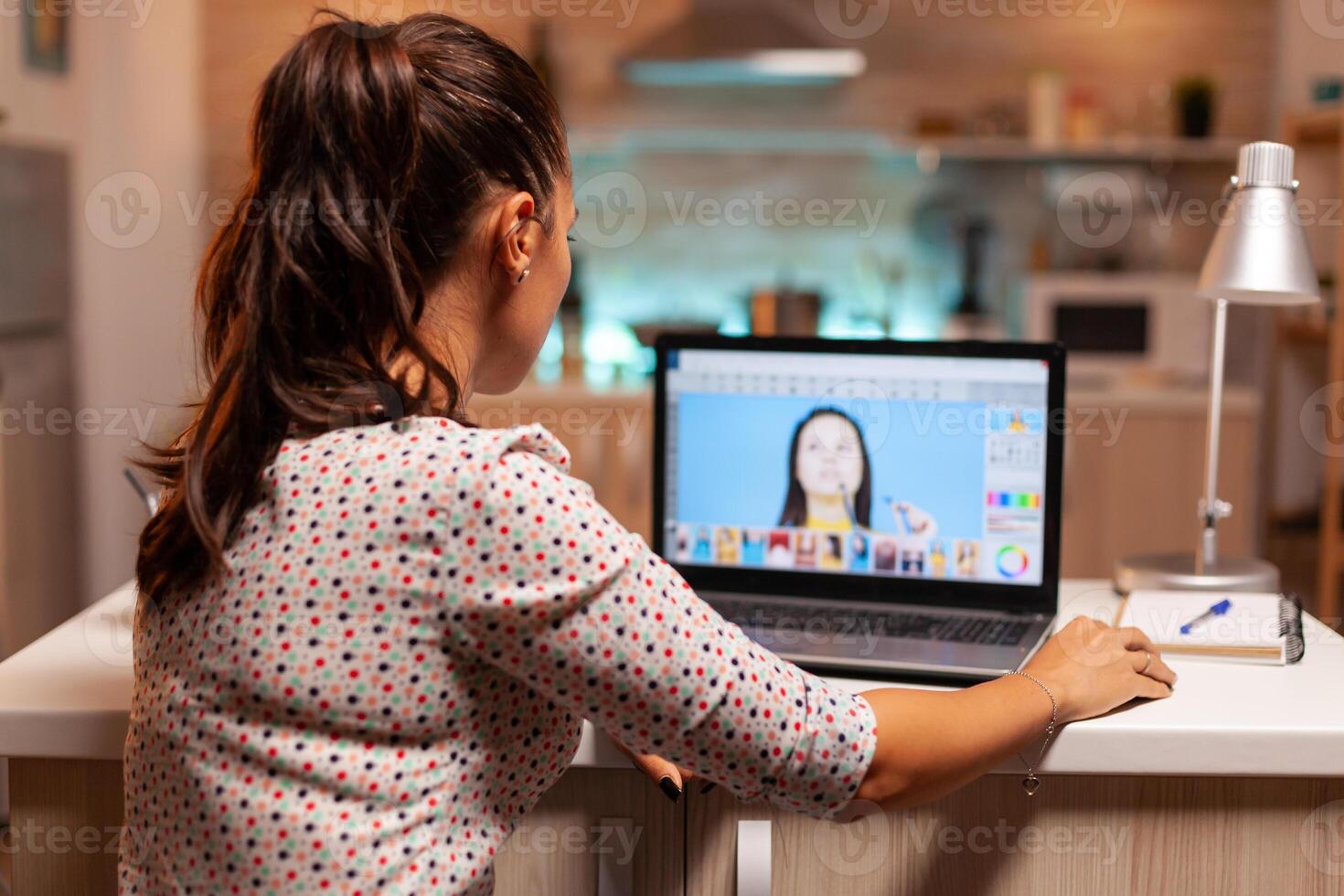 Professional graphic editor retouching photos of a client during night time in home office. Photographer doing portrait post production using software and performance laptop, artist, occupation, screen, graphic